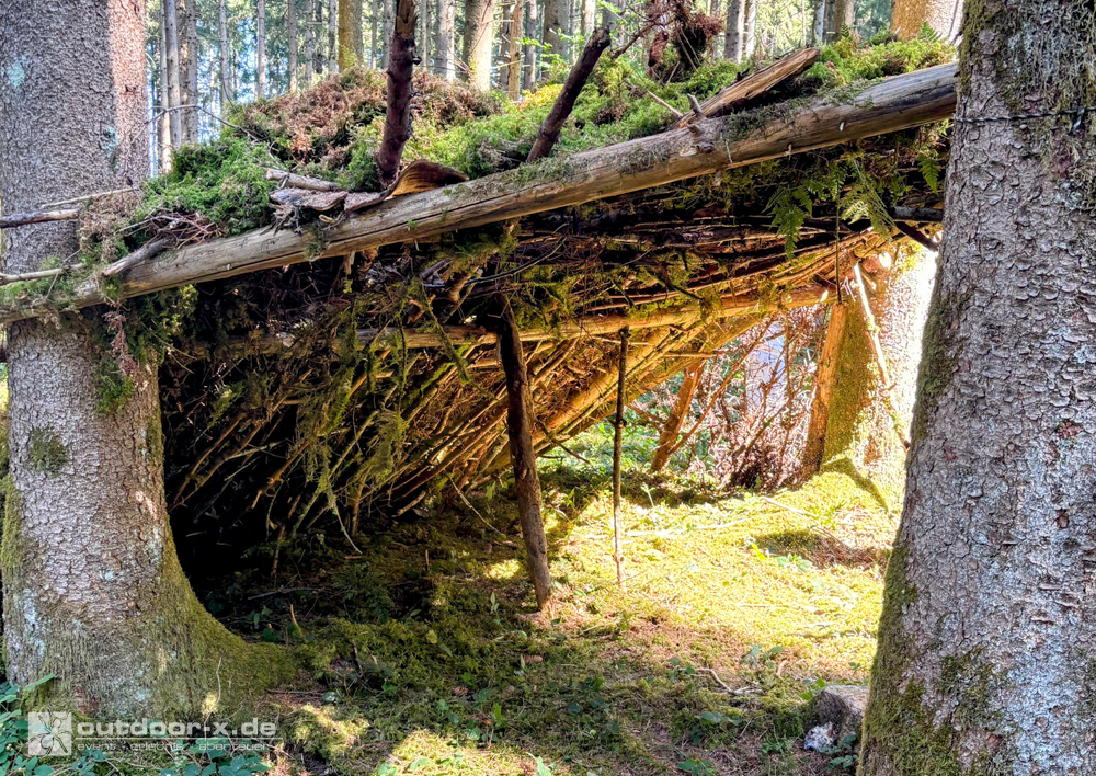 Fertiggestellter Shelter aus Ästen und Moos beim Teambuilding für Schulklassen im Outdoor-Workshop der Outdoor-X Academy